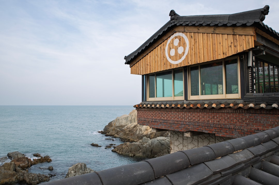 창밖으로 푸른 바다가 시원하게 펼쳐진 오션뷰 카페 내부 전경. 따뜻한 햇살이 들어오는 통창 옆으로 편안한 좌석들이 놓여있고, 바다와 어우러지는 현대적인 인테리어가 돋보입니다.