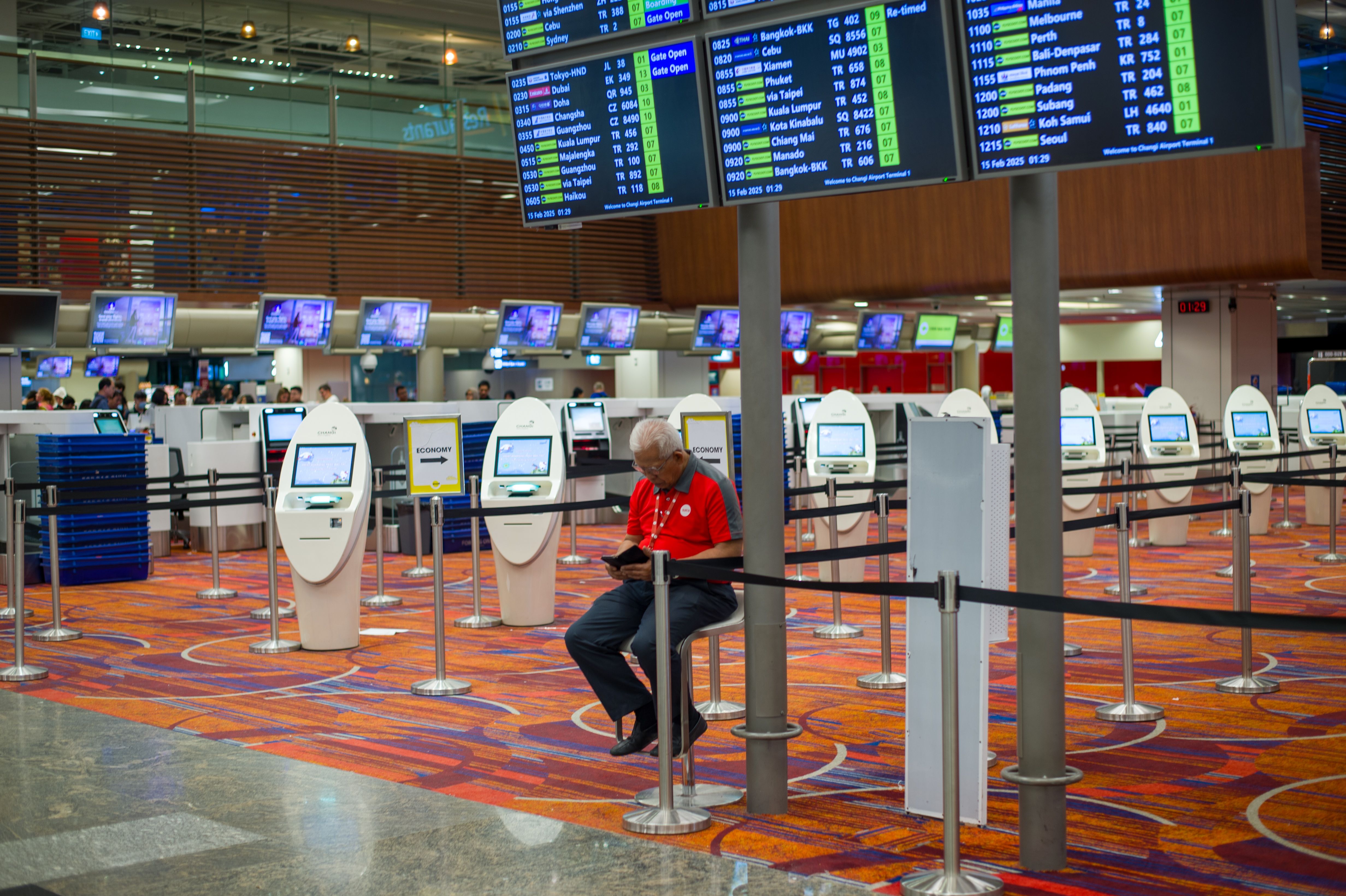 디지털 키오스크가 있는 현대적인 공항 출입국 심사대, 얼굴 인식과 지문 등록을 준비하는 여행객들